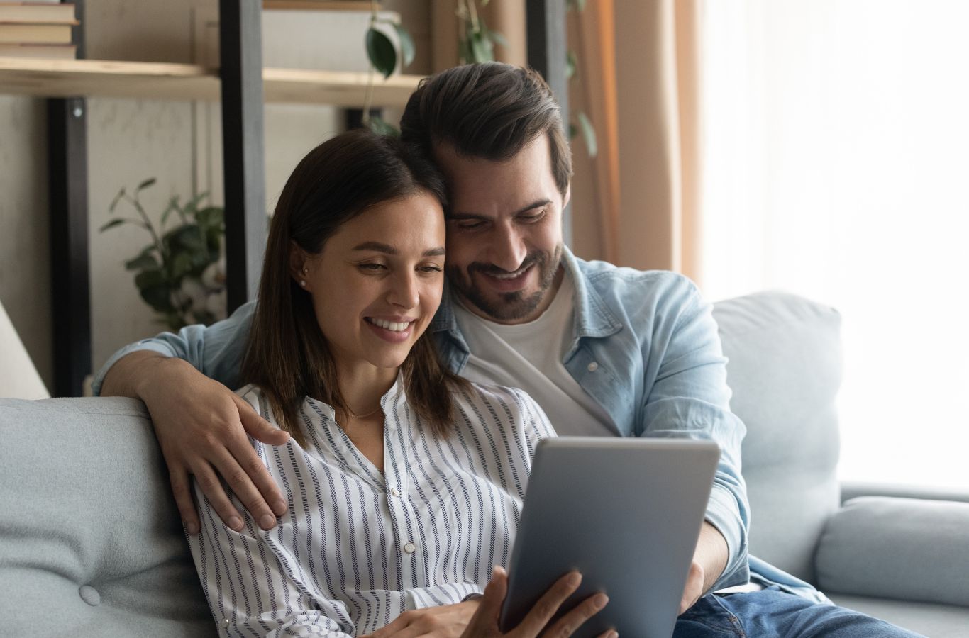 couple sitting on a couch reading on tablet